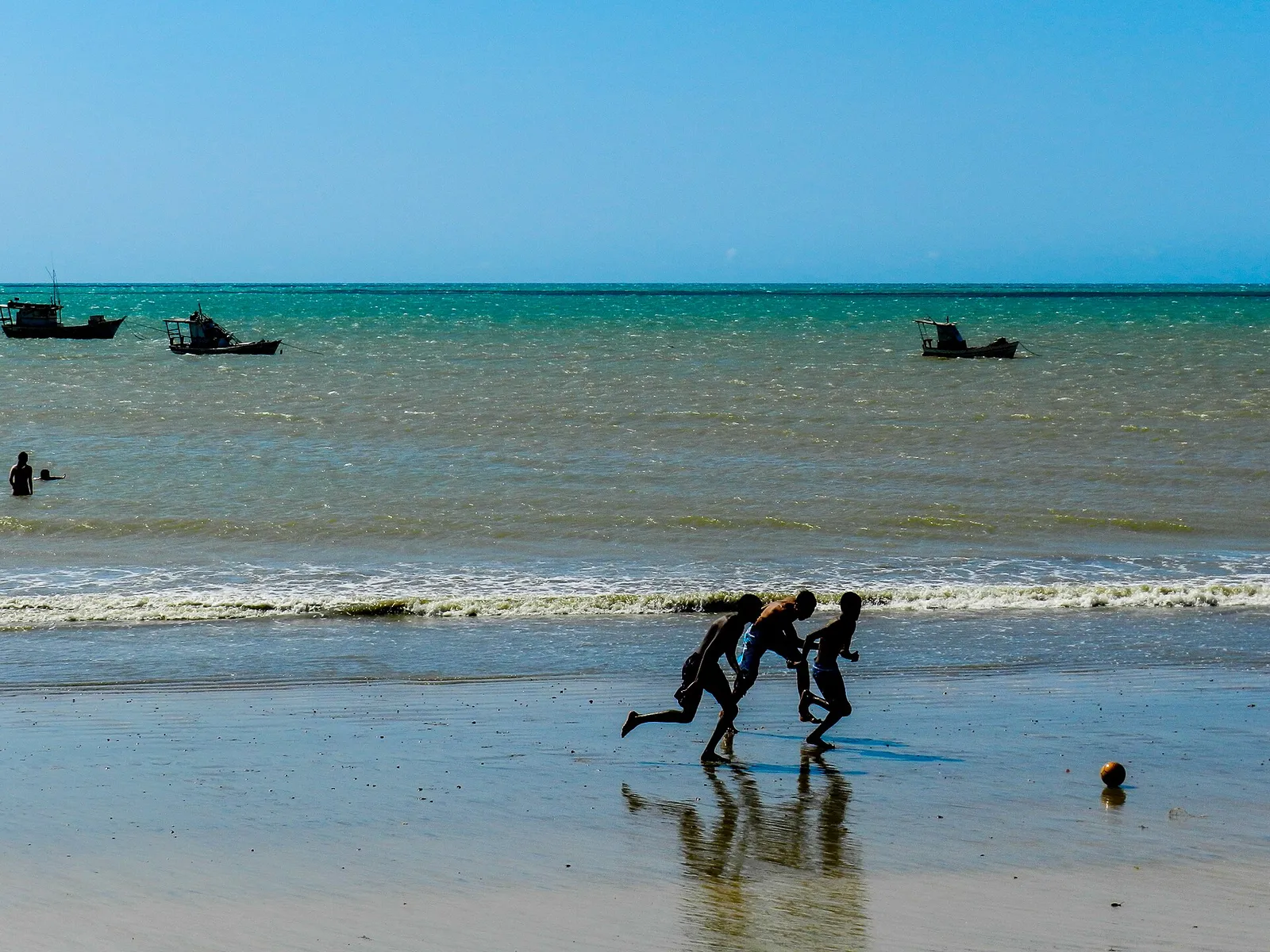 Crianças jogando futebol na praia
